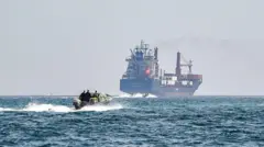 2025 年 6 月 25 日，在阿曼北部穆桑达姆半岛卡哈卜海岸附近的霍尔木兹海峡水域，一艘船只靠近悬挂圣基茨和尼维斯国旗的集装箱船 “马尔萨胜利号”。