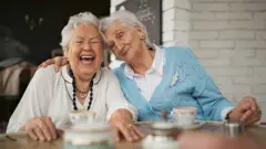 Una mujer riendo junto a una amiga