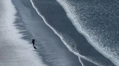 Uma pessoa andando sozinha na praia