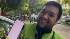 Seorang pengemudi ojol menujukkan aplikasinya.