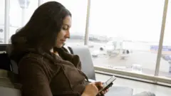 በአየር ማረፊያ ስልኳን የምትጠቀም ሴት