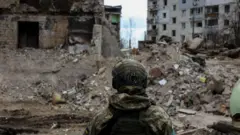 Um militar observa os escombros de edifícios destruídos por bombardeios russos, em meio à invasão russa da Ucrânia, em Borodyanka, região de Kiev, Ucrânia, 11 de abril de 2022