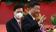 Hong Kong's new Chief Executive John Lee walks with China"s President Xi Jinping following Xi's speech after a ceremony to inaugurate the city's new leader and government in Hong Kong, China, July 1, 2022, on the 25th anniversary of the city's handover from Britain to China