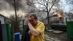 Ukraine man crying in front of a burning building