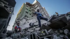 Palestinians inspect the rubble of their destroyed house after Israeli airstrikes