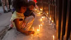 Children light candles at the entrance gate of the Sacred Heart Cathedral in Delhi, India. Photo: 24 December 2020