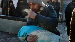 Сириец в Идлибе с телом ребенка