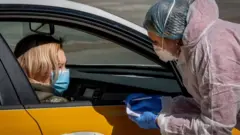 A medical staff wearing a protective suit speaks with a woman near a testing point for Covid-19 in central Moscow