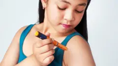 अपने आपको इंसुलिन का इंजेक्शन देती हुई एक बच्ची