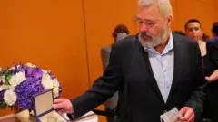 Dmitry Muratov posa en el Time Center junto a su medalla del Nobel de la Paz en 2022.