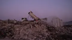 самосвал на руинах дома