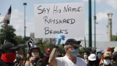 A protester holds a sign with Rayshard Brooks' name in Atlanta