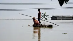 Une femme et un enfant sur un radeau dans un village inondé.