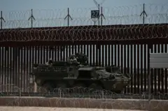 Un vehículo blindado estadounidense en la frontera cerca de El Paso, con una valla y alambre de púas detrás del tanque.