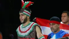 Prichard Colon wear sparkly red, silver and green vest and headband wit feathers