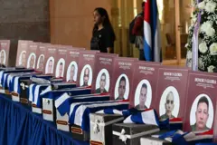 Urnas com os restos mortais dos 32 soldados cubanos que morreram durante a incursão dos EUA para capturar o líder venezuelano Nicolás Maduro, em honras fúnebres no Ministério das Forças Armadas Revolucionárias, em Havana, com retrato dos soldados, medalhas e flores