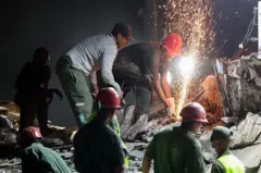 उद्धारकर्मीहरू भवनका भग्नावशेषमा खोजी गर्दै
