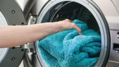 toalha sendo colocada na máquina de lavar