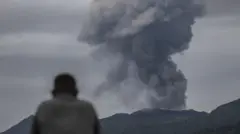 Um socorrista observa o vulcão Monte Dukono durante sua erupção em Halmahera Norte, Indonésia, em 9 de maio de 2026. De acordo com a agência de resgate da Indonésia (Basarnas), os socorristas recuperaram o corpo de um excursionista indonésio, enquanto dois excursionistas de Singapura continuam desaparecidos.