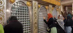 سيدات يستندن بأيديهن ورؤوسهن إلى ضريح الإمام الحسين في القاهرة