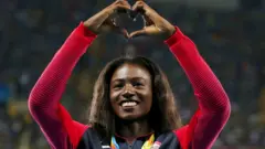 Bronze medalist Tori Bowie makes a heart sign with her hands at the Women's 200m Victory Ceremony for the 2016 Rio Olympics 