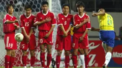 Jogadores chineses na barreira enquanto Roberto Carlos (dir.) cobra uma falta para marcar um gol do Brasil durante a Copa do Mundo de 2002, aos 14 minutos de jogo