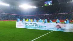 Trabzonsporlu futbolcular Rizespor'a karşı oynadıkları Türkiye Kupası maçında üzerinde "Doğal olan normal doğum" yazılı bir pankart taşıyor.