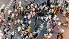 O intersecție urbană din Madrid este văzută de sus. O mulțime de oameni, de toate vârstele, traversează dezordonat strada.