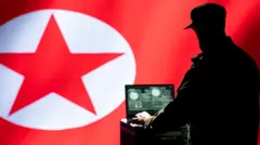 Imagen que muestra a un hombre con gorra y uniforme trabajando en un computador portátil con una bandera de Corea del Norte como fondo.