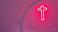 Una luz en forma de cruz de neón rosa colgada en una discoteca.