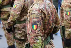 Des soldats de l'armée malienne marchant au cours d'un défilé vêtus d'uniformes de camouflage et d'écussons avec le drapeau national aux couleurs vert, jaune et rouge.