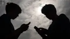 صورة لخيال طفليين لاتبدو ملامحهما يقفان وجها لوجه وكل منهما يتصفحه هاتفه النقال