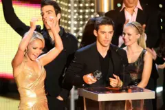 Hayden Panettiere com os braços erguidos comemorando ao lado de vários colegas de elenco.