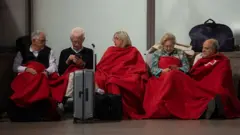 People sit waiting at a Spanish station for the power to come back on in April 2025