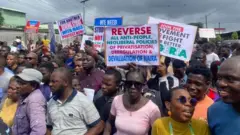 Protesters carry different placards to protest end to band governance for August