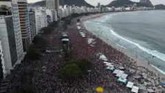 Foto aérea da orla de Copacabana lotada de pessoas.
