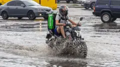 чоловік на мотоциклі на затопленій дорозі