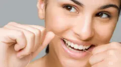 Uma mulher sorri enquanto usa fio dental
