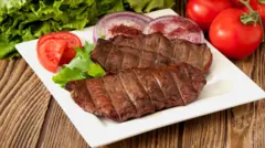 Um prato com um pedaço de fígado e tomates em volta