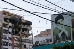 Beyrut'un güneyindeki Haret Hreik semtinde, İsrail'in hava saldırısının ardından hasar gören bir binanın yakınında, eski Hizbullah lideri Hasan Nasrallah'ın fotoğrafının bulunduğu bir reklam panosu görülüyor. 2 Mart 2026. 