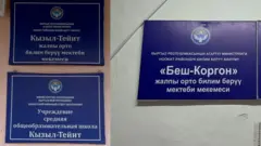 Ош облусунун Ноокат районундагы бир имаратта жайгашкан эки мектептин аталышы жазылган тактайчалар
