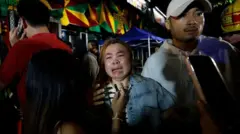 Um parente de uma vítima chora do lado de fora do bar em Bangkok que foi atingido por um incêndio violento.
