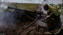 Un soldat ukrainien accroupit devant un lance-grenades