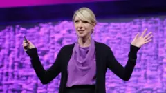 سيدة تتحدث على المسرح وتفتح يديها