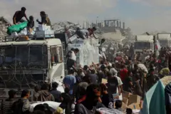 Una muchedumbre se arremolina junto a camiones de reparto de ayuda en Jan Yunis, Gaza.