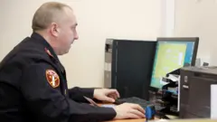 Полицейский смотрит в экран компьютера