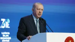 Erdoğan İstanbul'da 3. Dünya İslam Ekonomisi zirvesi'nde kürsüden konuşuyor, arkada mavi bir zemin var
