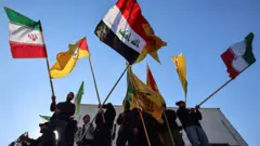 پرچم ایران، عراق و گرو‌های مسلح عراقی نزدیک به ایران در دست معترضانی که در نزدیک سفارت جمهوری اسلامی در بغداد به تهدیدهای اخیر آمریکا و اسرائیل علیه تهران اعتراض می‌کنند.