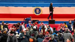 Sahnede başkanlık logosu, önünde kalabalık hazırlık yapıyor