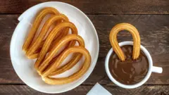 Prato de churros e caneca de chocolate cremoso
